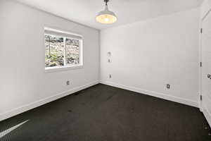 Empty room featuring dark carpet and baseboards