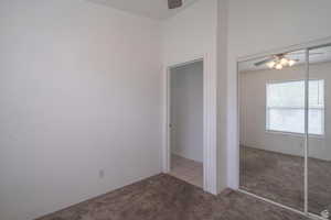 Unfurnished bedroom with ceiling fan, light carpet, and a closet