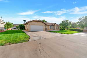 View of front of house with a front yard, driveway, a garage, and stucco siding