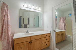 Bathroom with vanity, shower / bath combination with curtain, and light tile patterned floors