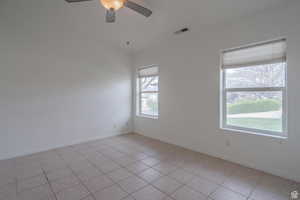 Empty room with light tile patterned floors and a ceiling fan