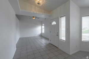 Foyer entrance featuring light tile patterned floors, ceiling fan, and vaulted ceiling