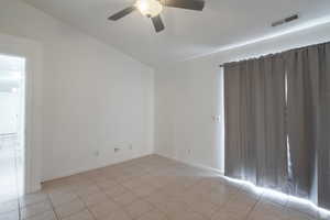 Empty room with lofted ceiling, a ceiling fan, and light tile patterned flooring