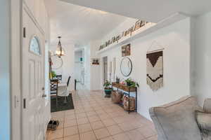 Foyer entrance with light tile patterned floors and suspended lighting
