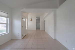 Entryway with healthy amount of natural light, a chandelier, and light tile patterned flooring