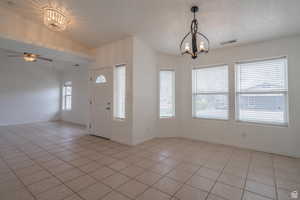 Entrance foyer featuring suspended lighting, light tile patterned floors, ceiling fan, and lofted ceiling