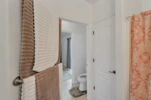 Full bath with curtained shower and light tile patterned floors