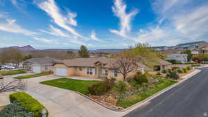Single story home featuring driveway, stucco siding, a residential view, and an attached garage