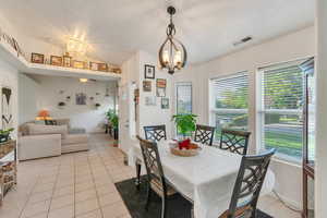Dining area with light tile patterned floors, hanging lights, and lofted ceiling