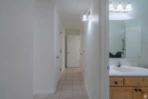 Hallway featuring light tile patterned floors and a sink