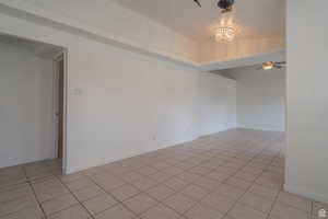 Spare room with light tile patterned floors, a chandelier, and ceiling fan