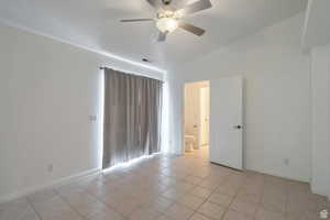 Spare room featuring ceiling fan, lofted ceiling, and light tile patterned floors