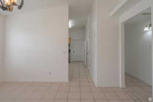 Hallway with a chandelier and light tile patterned floors