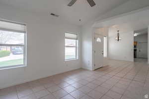 Foyer with light tile patterned floors, lofted ceiling, a ceiling fan, and a chandelier