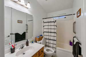 Bathroom with vanity, shower / tub combo with curtain, and vaulted ceiling