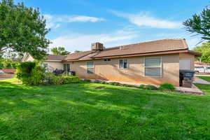 Back of property with stucco siding, a yard, and a tiled roof