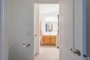 Bathroom with a shower with shower curtain, light tile patterned flooring, and vanity