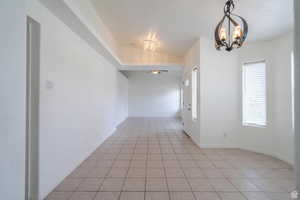 Empty room with a chandelier and light tile patterned floors