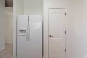 Kitchen view of white fridge with ice dispenser and baseboards