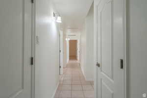 Corridor featuring attic access and light tile patterned floors