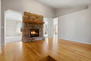 Front entry featuring vaulted ceiling, a stone fireplace, and light wood-style floors