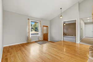 Foyer entrance featuring vaulted ceiling, light wood-type flooring, and ceiling fan