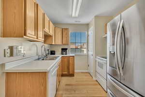 Kitchen featuring white appliances, light countertops, light wood-type flooring, and light wood finish cabinets