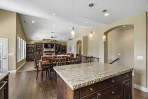 Kitchen featuring dark wood finish cabinetry, dark wood-type flooring, open floor plan, a kitchen island, and a ceiling fan
