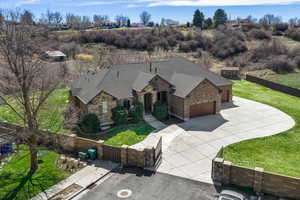 View of front of home with concrete driveway, an attached garage, roof with shingles, stone siding, and a gate
