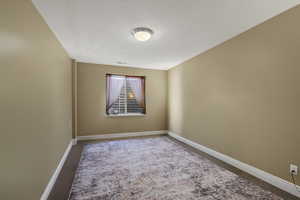 Empty room with light carpet and a textured ceiling