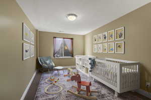 Bedroom featuring a crib, carpet flooring, and a textured ceiling