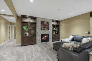 Carpeted living area featuring a stone fireplace, built in features, and recessed lighting