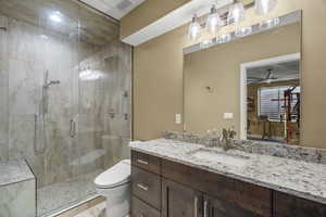 Bathroom with vanity, a shower stall, and a ceiling fan