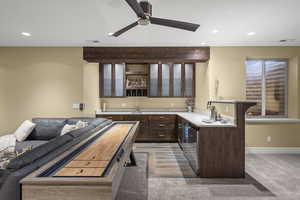 Indoor wet bar with glass insert cabinets, dark wood finish cabinetry, light countertops, recessed lighting, and a ceiling fan