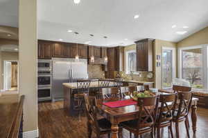 Dining space with dark wood finished floors, arched walkways, a textured ceiling, and recessed lighting