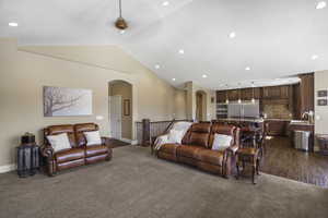Living room featuring arched walkways, recessed lighting, and dark carpet