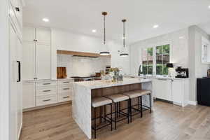 Kitchen with light wood-type flooring, light stone counters, a kitchen island, and a breakfast bar area
