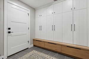 Mudroom featuring dark tile patterned flooring and baseboards