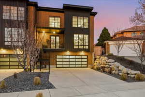 View of front of property with brick siding, board and batten siding, concrete driveway, and a balcony
