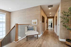 Corridor with light wood-style flooring and an upstairs landing