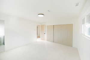 Unfurnished bedroom with light colored carpet and a closet
