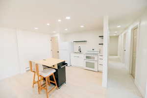 Kitchen with white appliances, recessed lighting, light countertops, open shelves, and white cabinetry