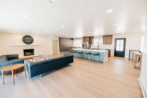 Living area featuring light wood-style flooring, a baseboard heating unit, a fireplace, healthy amount of natural light, and recessed lighting