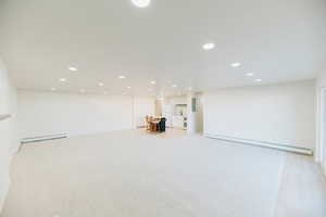 Below grade area with baseboard heating, recessed lighting, and light carpet