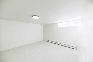 Empty room with a baseboard radiator and light colored carpet