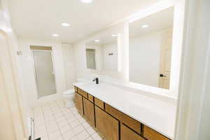 Full bath featuring vanity, recessed lighting, light tile patterned floors, a shower stall, and a closet