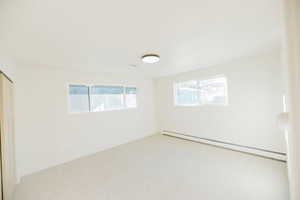 Unfurnished room with a baseboard heating unit and light colored carpet
