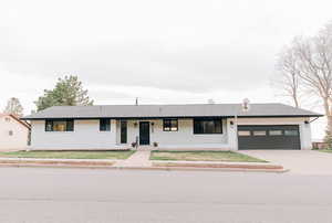 Ranch-style house featuring a garage, driveway, covered porch, and brick siding