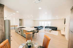 Kitchen featuring stainless steel appliances, a kitchen island, light wood-type flooring, open floor plan, and a fireplace
