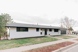 Ranch-style house with concrete driveway, a garage, brick siding, a front lawn, and a shingled roof